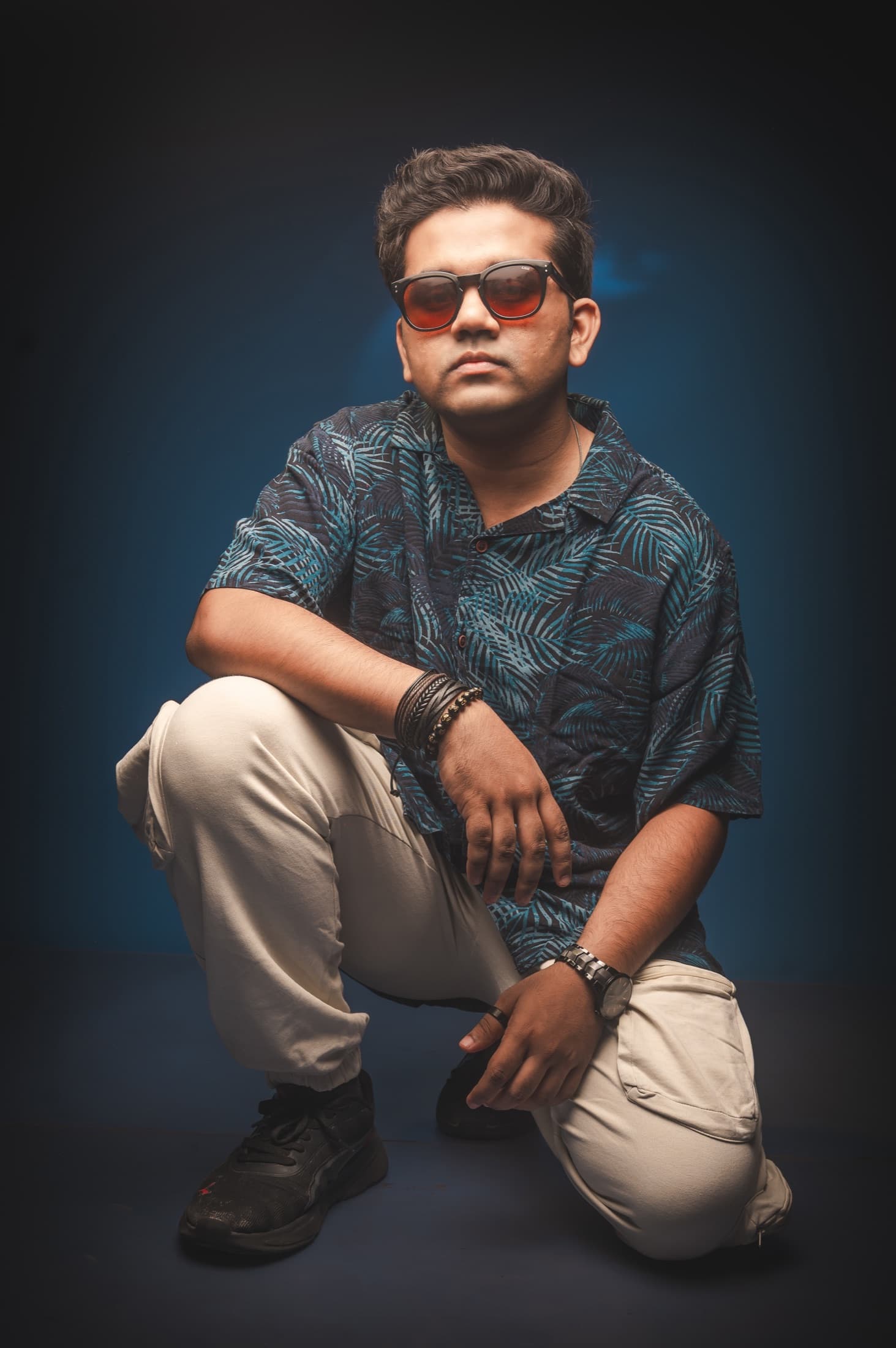 TRE crouched in a patterned shirt under blue light