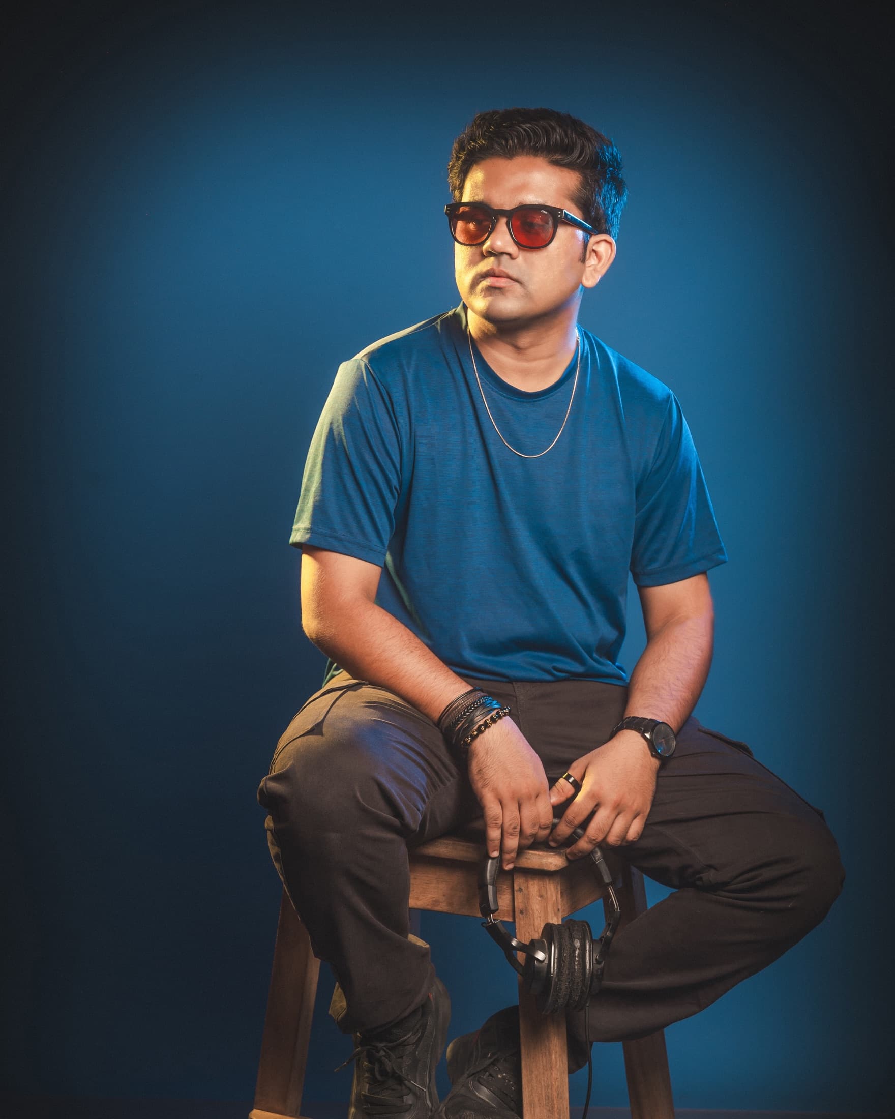 TRE seated on a stool against a blue backdrop